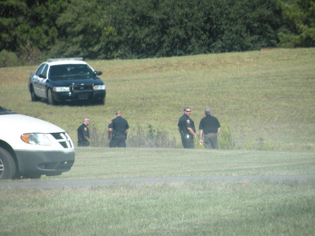 Police officers waiting in a field.